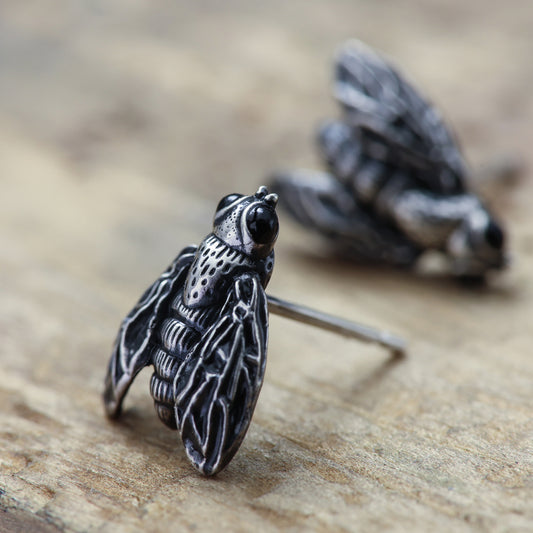 Close-up view of sterling silver fly earrings.