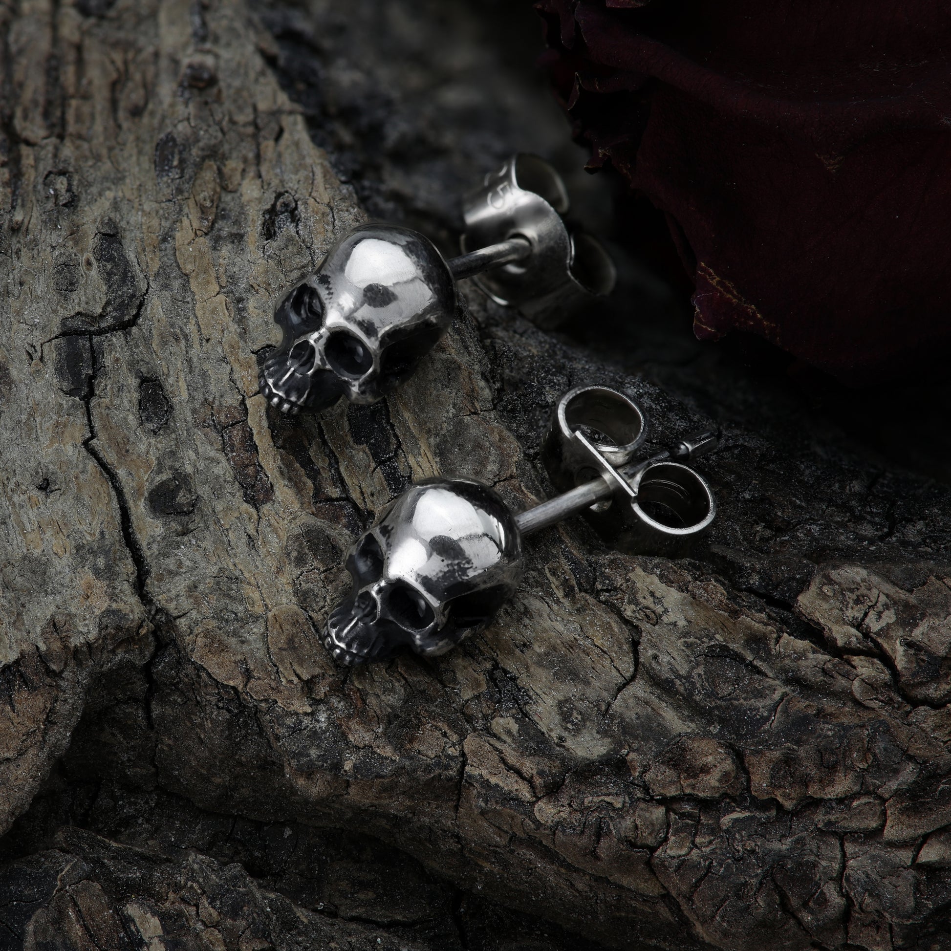 Angled view of miniature skull earring reflecting light.