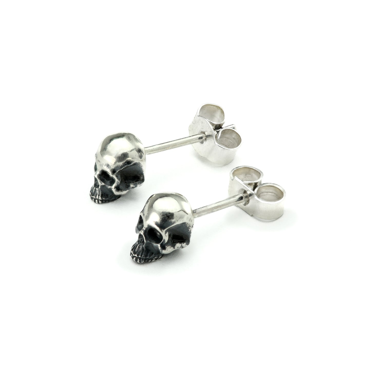 Pair of skull earrings laid on a white background showcasing their design.