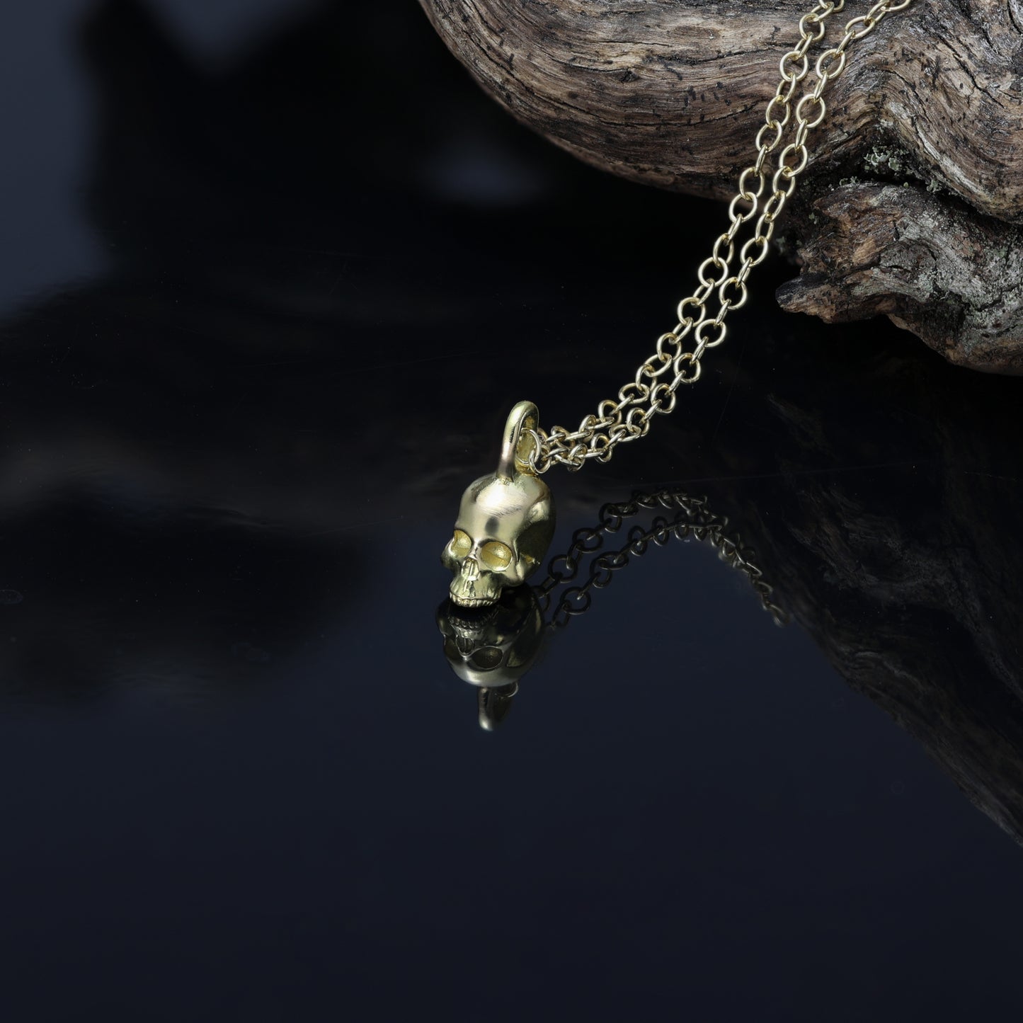 alt="Fine jewellery piece with a meticulously sculpted 18-carat gold skull pendant, hallmarked for authenticity."