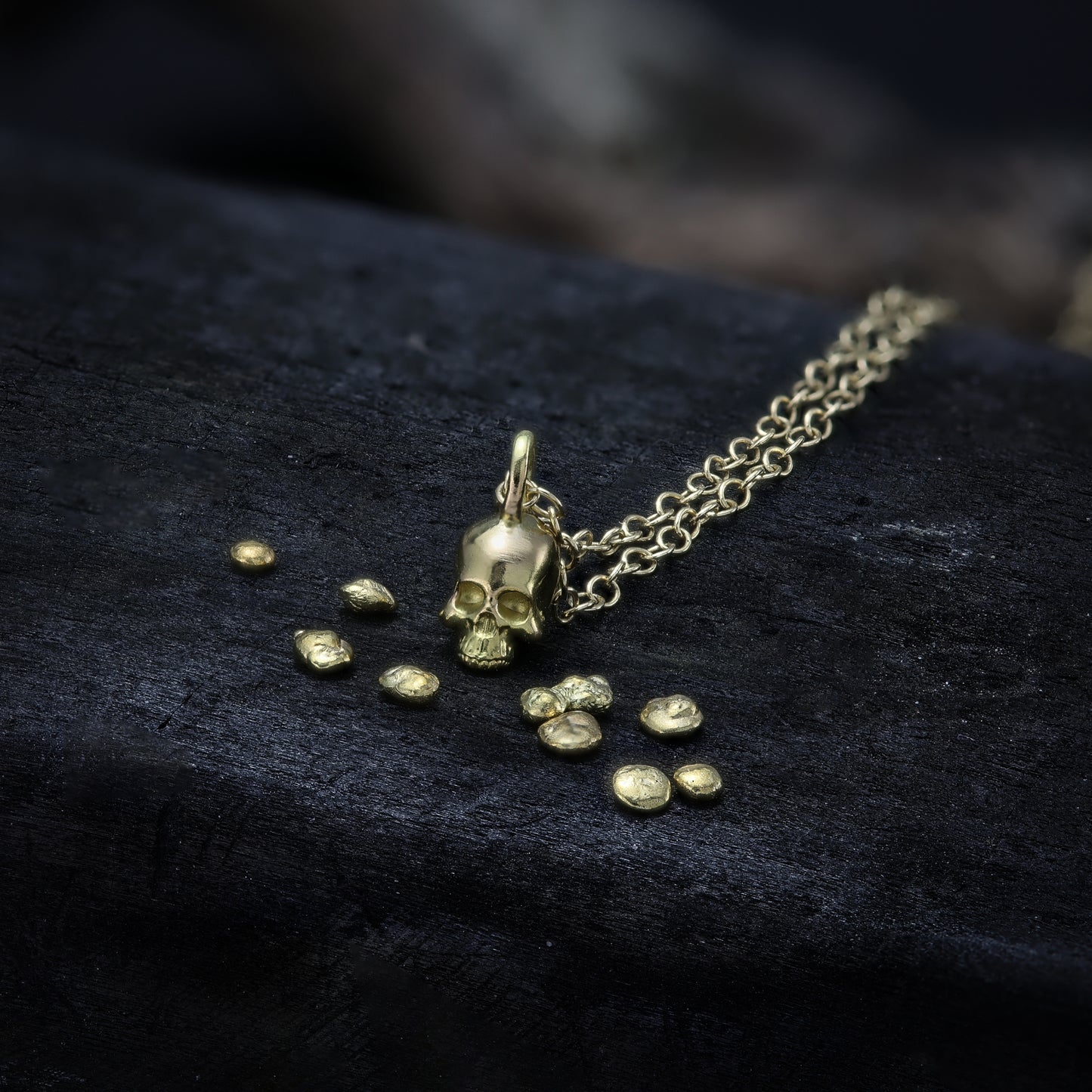 alt="Delicately sized golden skull necklace, representing the memento mori symbol."