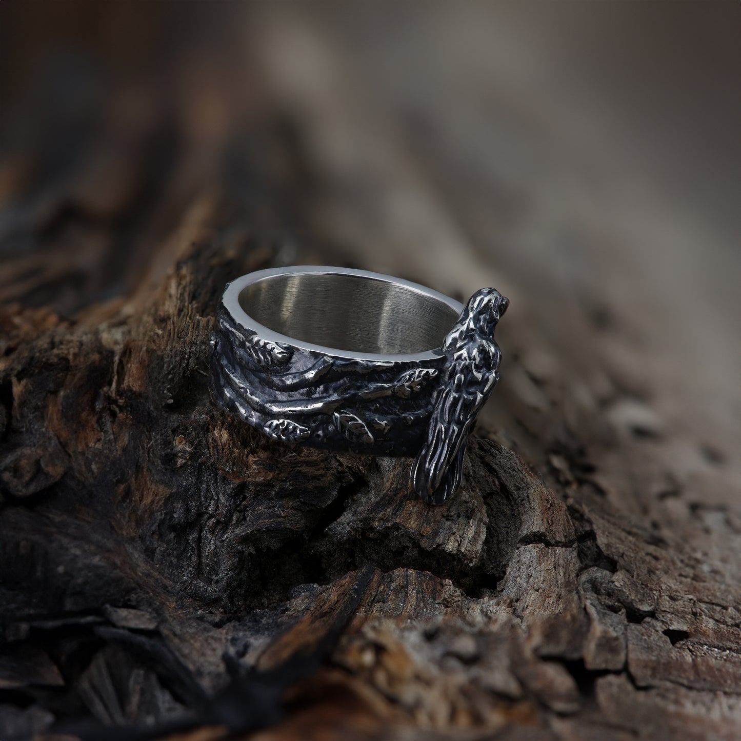 Angled view of sterling silver ring, emphasizing the intertwined twig pattern, placed on wood.