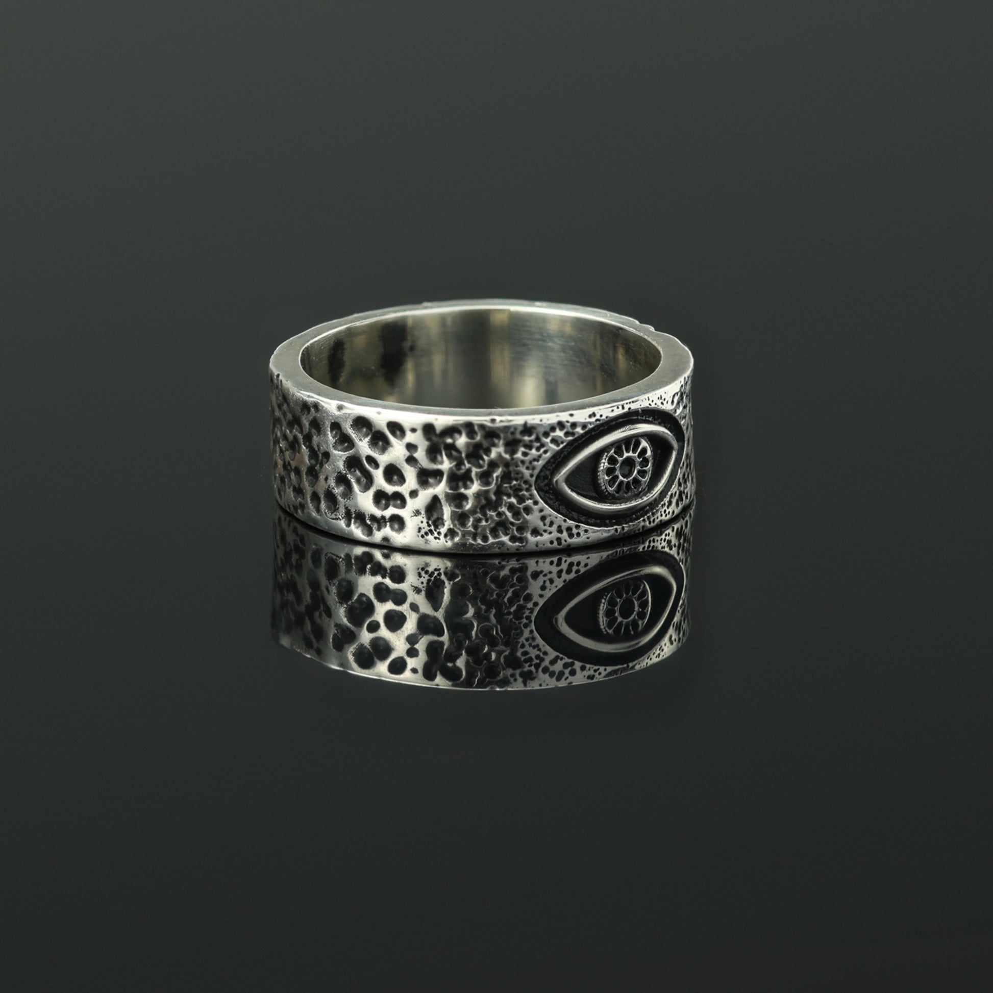 Textured silver band ring with eye detail.