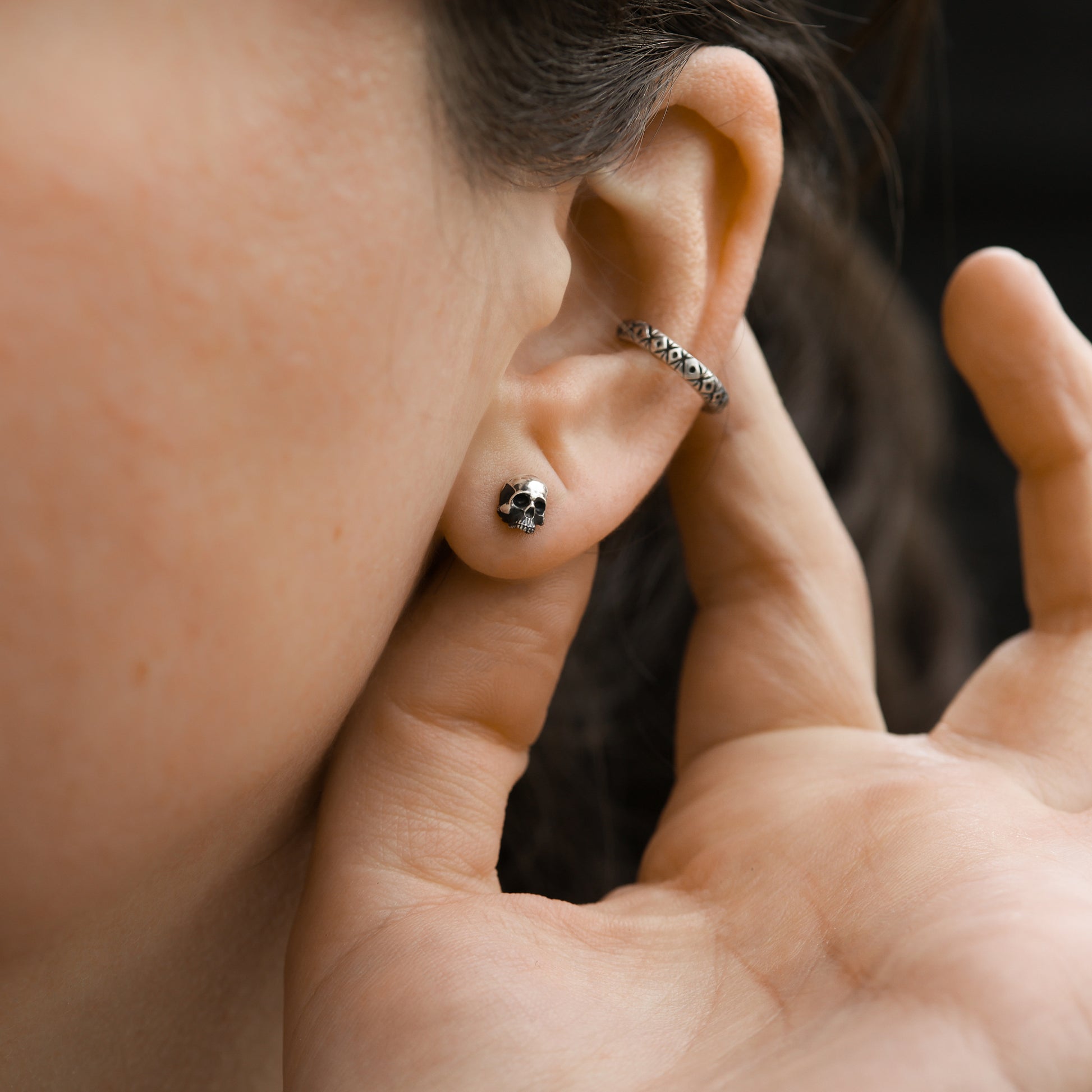 Skull stud earring in ear.