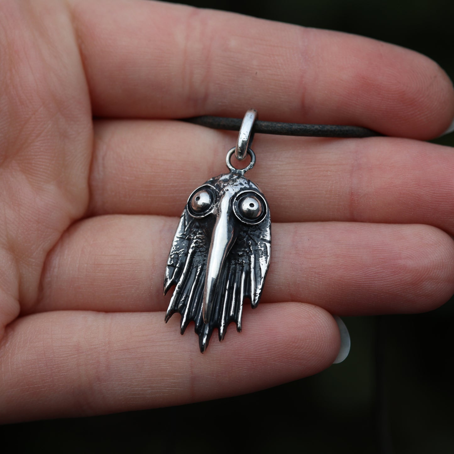 Sterling silver raven pendant with detailed artistry on palm