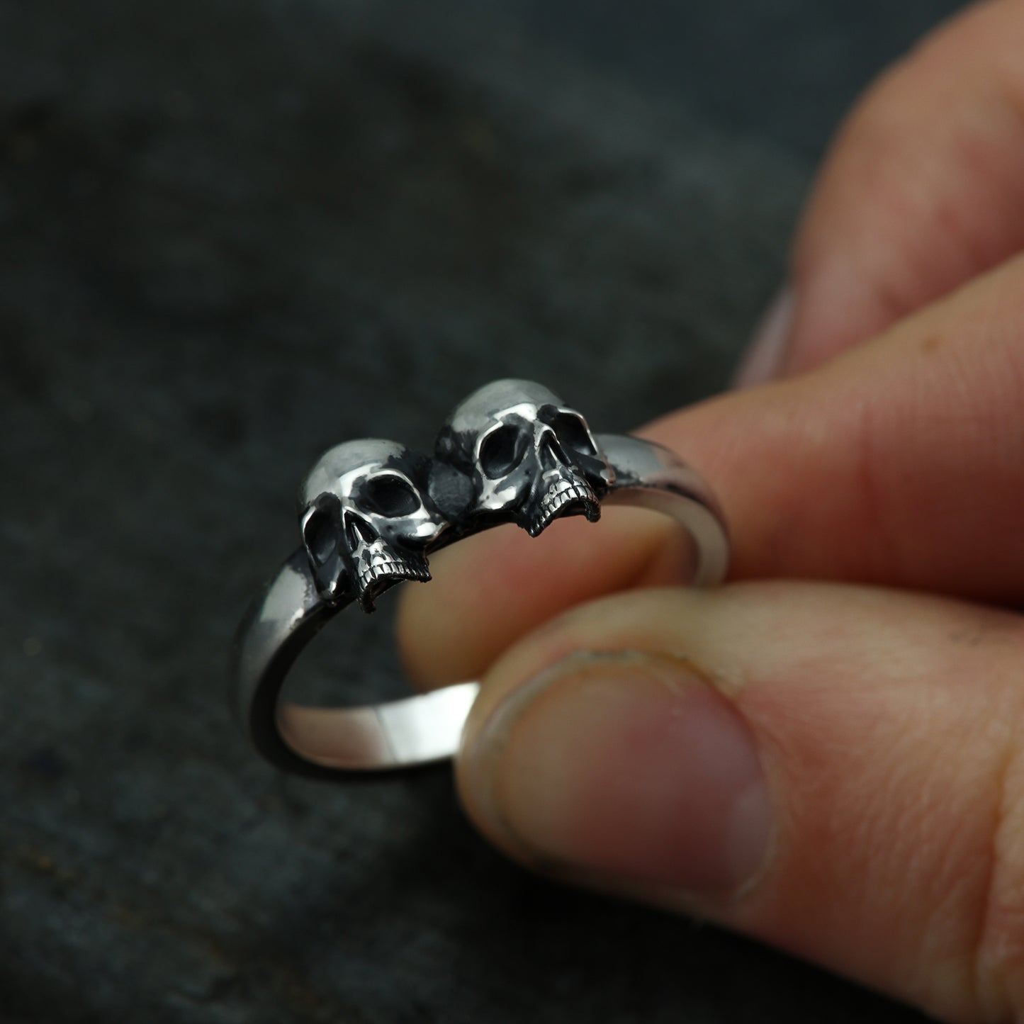 Side angle of sterling silver double skull band showing intricate design.