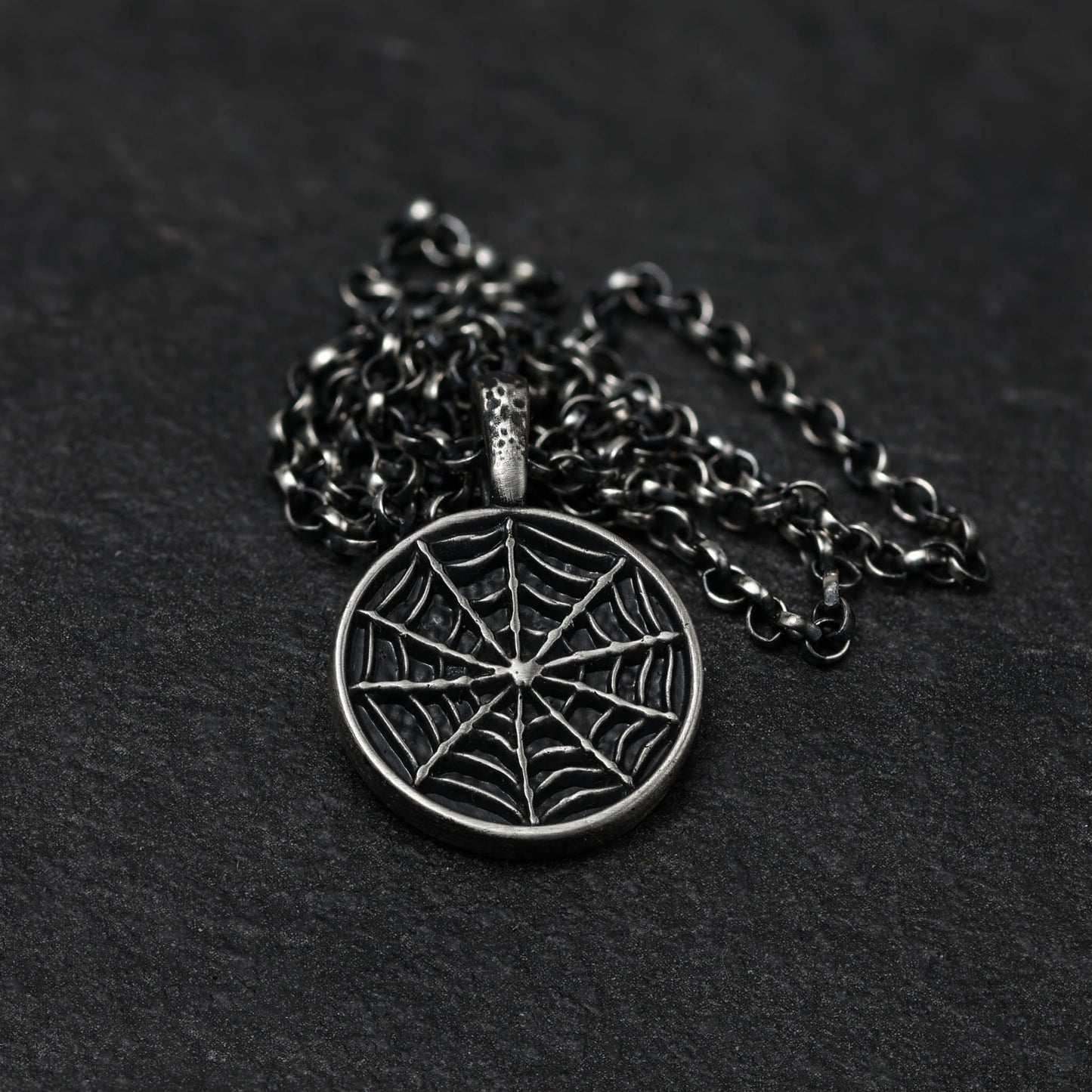 Sterling silver spider web necklace on a chain.