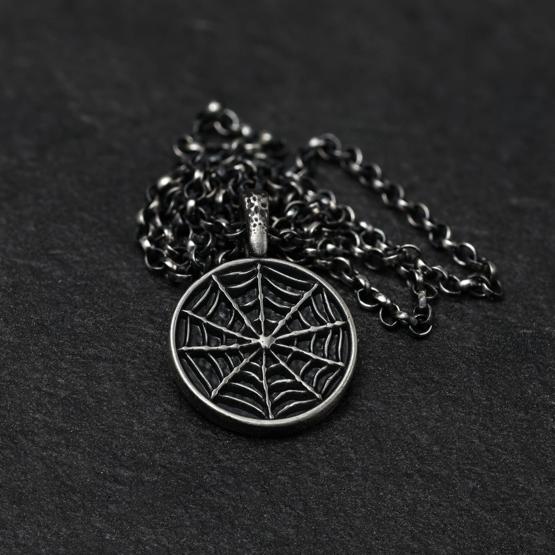 Sterling silver spider web necklace on a chain.
